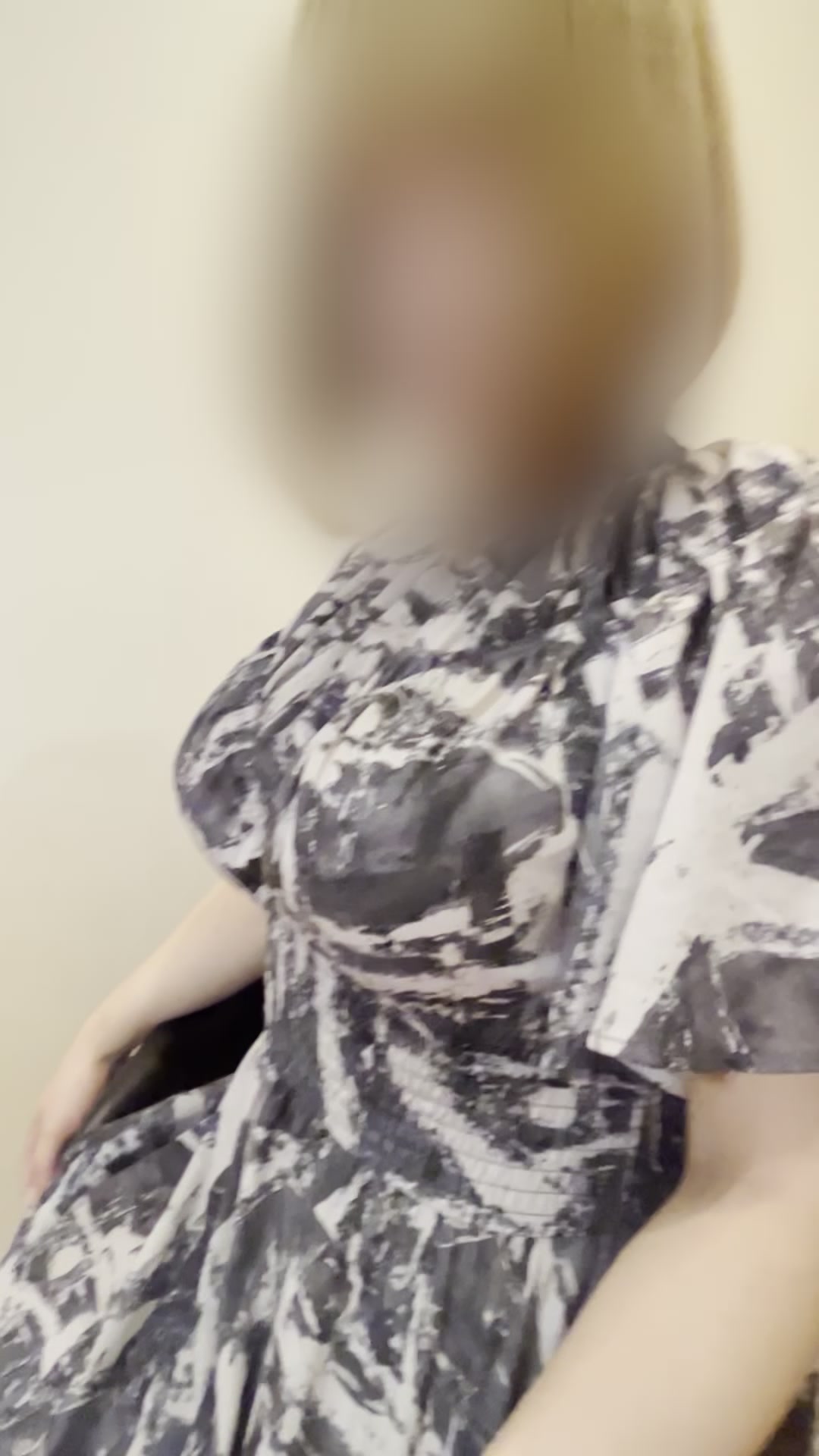 A woman in a patterned dress seated indoors, a clothed still from a Kaede video (face blurred in the original)