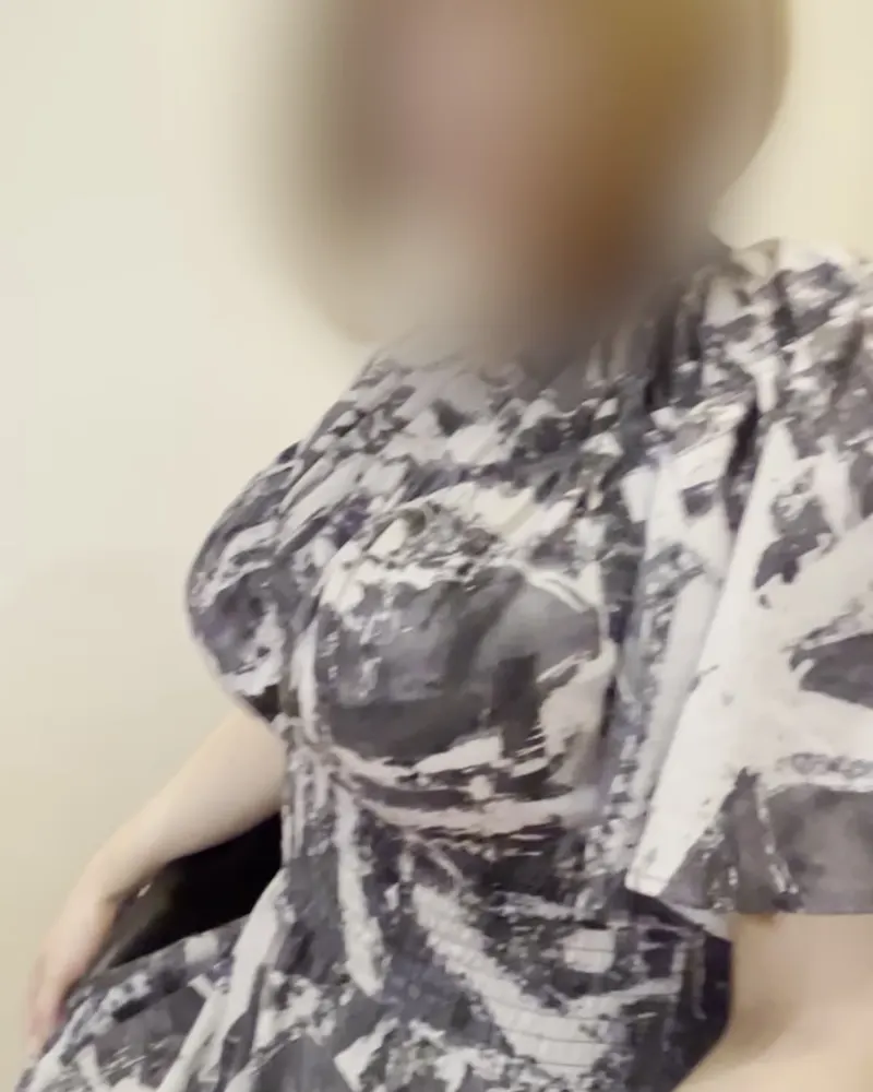 A woman in a patterned dress seated indoors, a clothed still from a Kaede video (face blurred in the original)