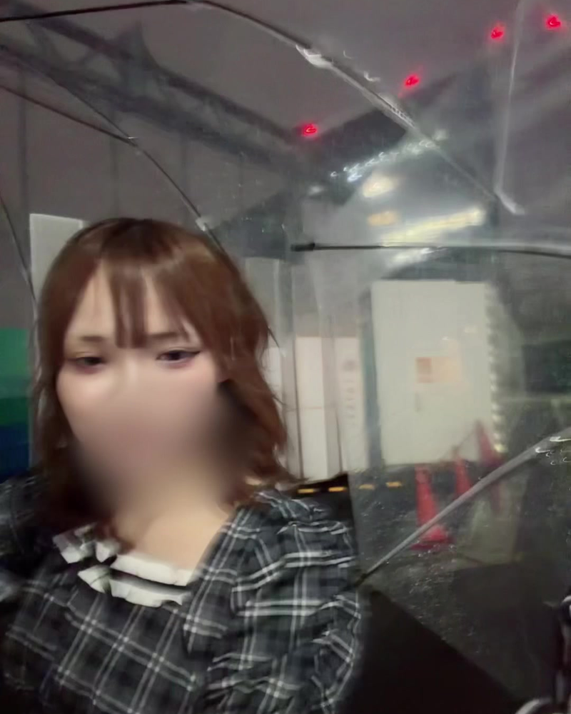 Clothed still from a video by Shinnosuke: a woman under a clear umbrella, face blurred
