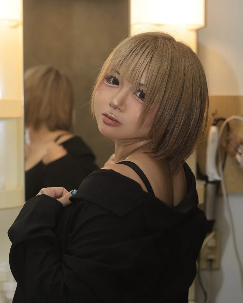 Tsuki in a black off-shoulder jacket, looking over her shoulder (photo from her X account)